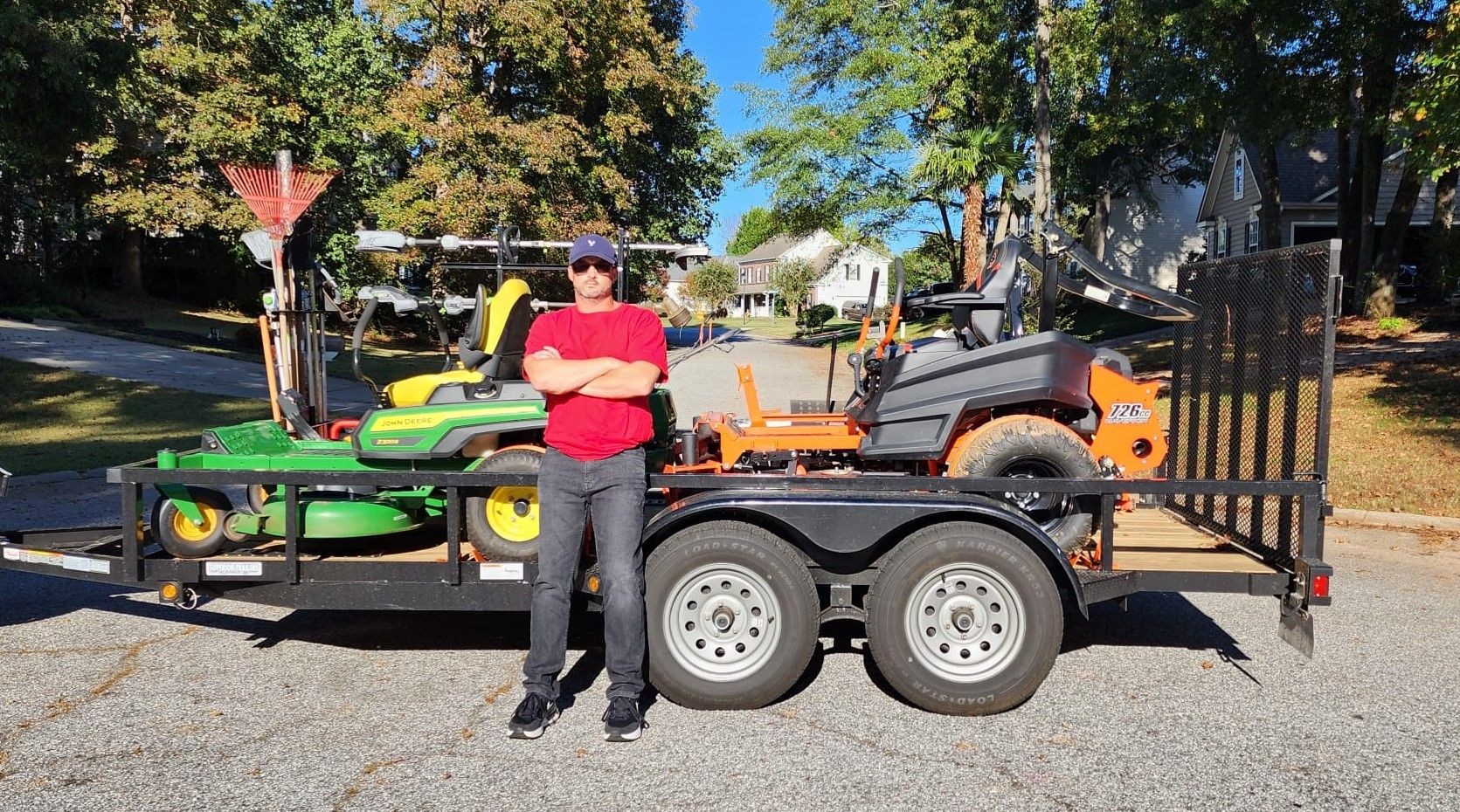 Man standing in front of trailer with lawn mowers and yard cleaning tools
